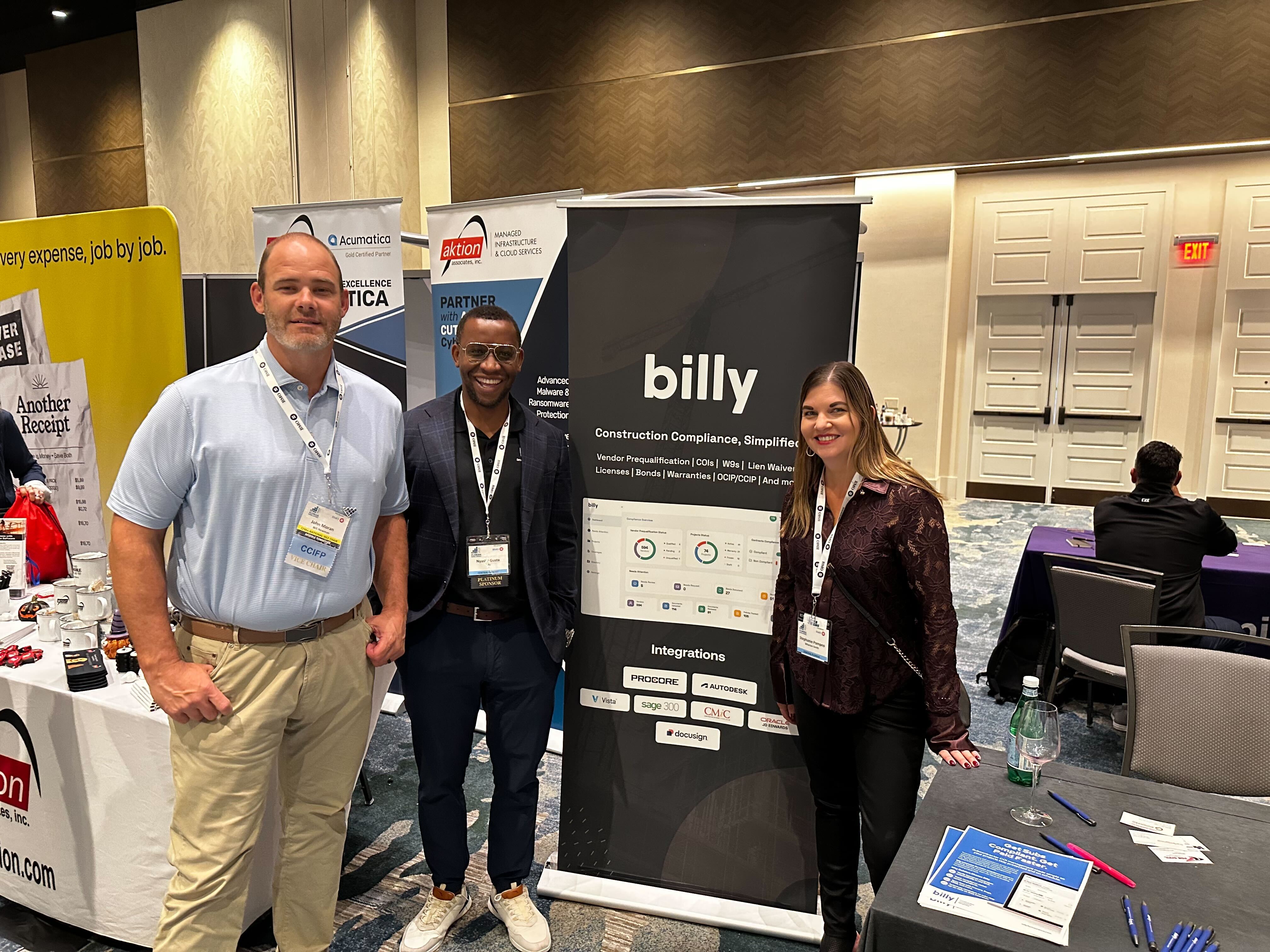 Nyasha Gutsa with two conference attendees beside the Billy banner listing Procore, Autodesk, Vista, Sage 300, CMiC, JD Edwards and Docusign integrations