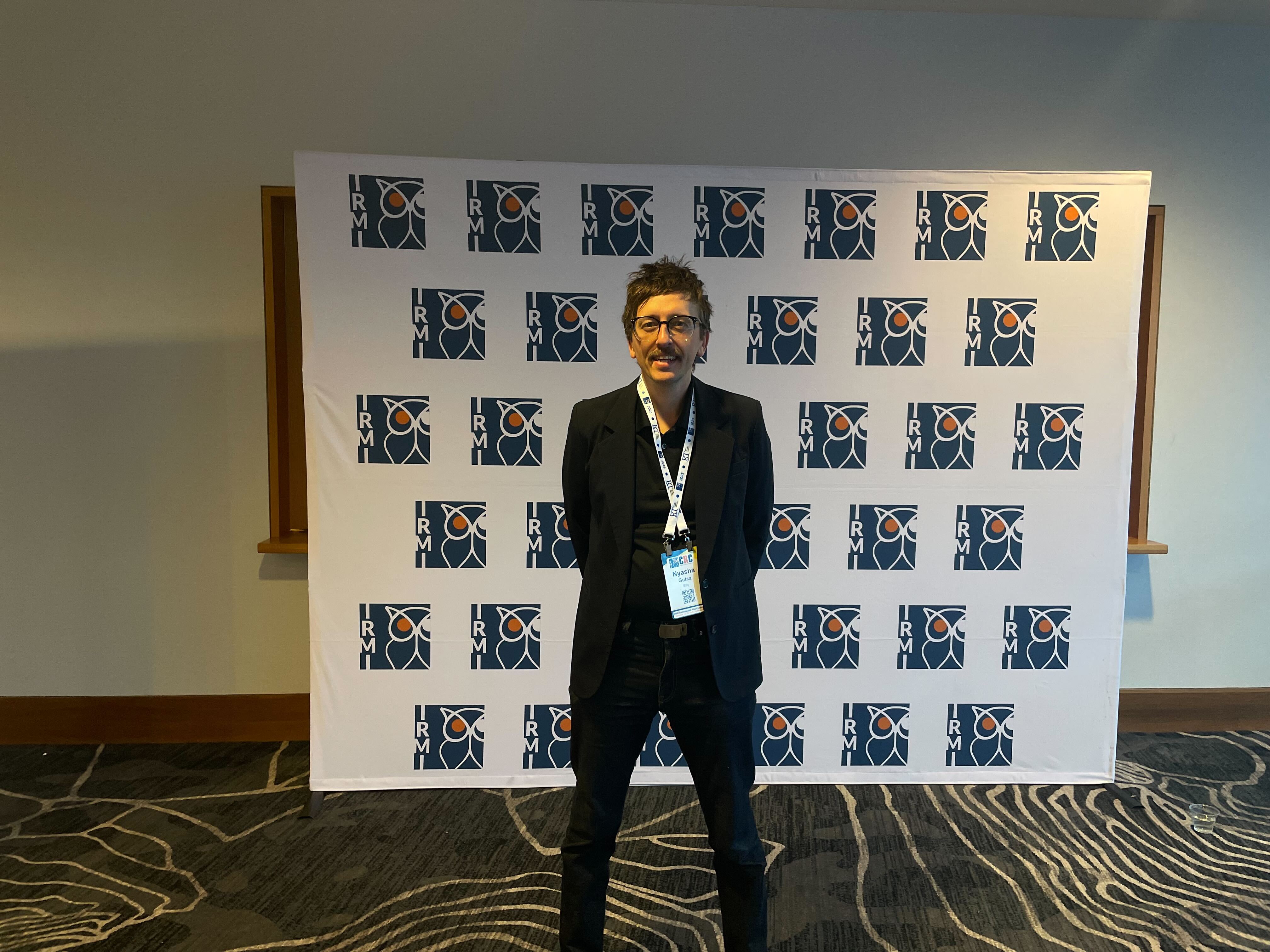 Nyasha Gutsa, Billy co-founder, in front of an IRMI backdrop wearing a CRC badge