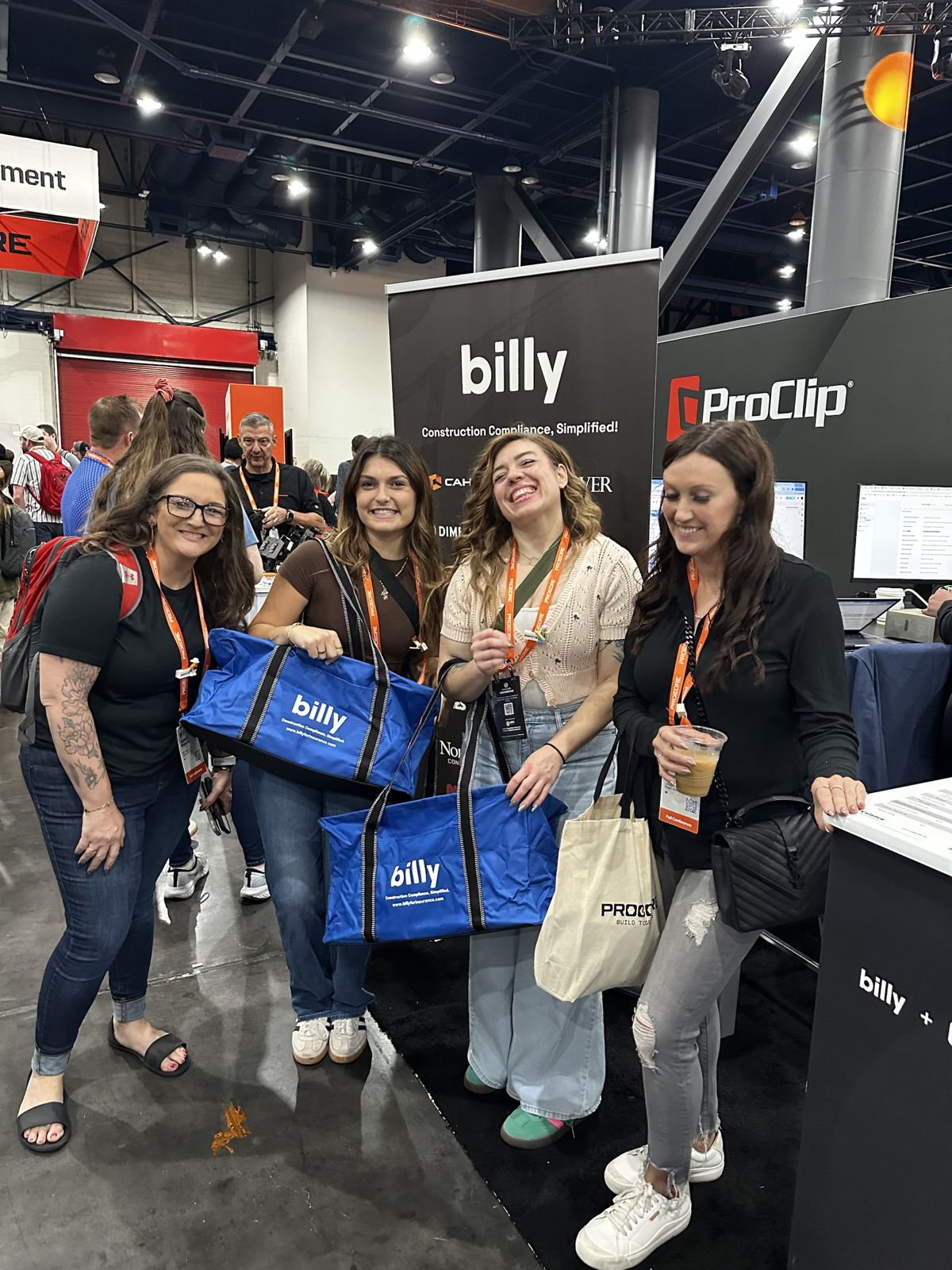 Attendees with Billy Construction Compliance Simplified tote bags at the Billy booth at Procore Groundbreak